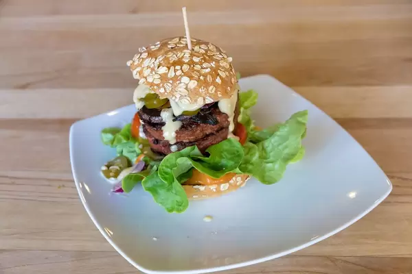 Beyond Meat Burger auf weißem Teller auf einem Holztisch in Bunte Burger Köln