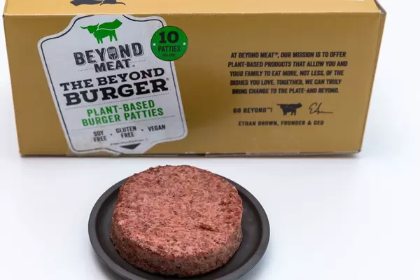 Beyond Meat Patty - a vegan, gluten free alternative of burger meat on black plate with its package in the background