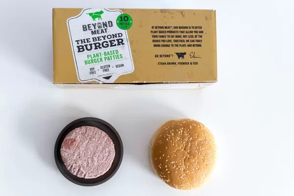 Beyond Meat veganisches glutenfreies Burger-Pastetchen auf schwarzem Teller mit Burger-Brötchen nebenan