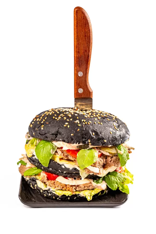 Big black burger with knife on white background