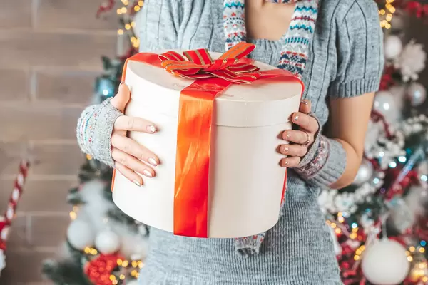 Big gift box with red ribbon and bow in female hands