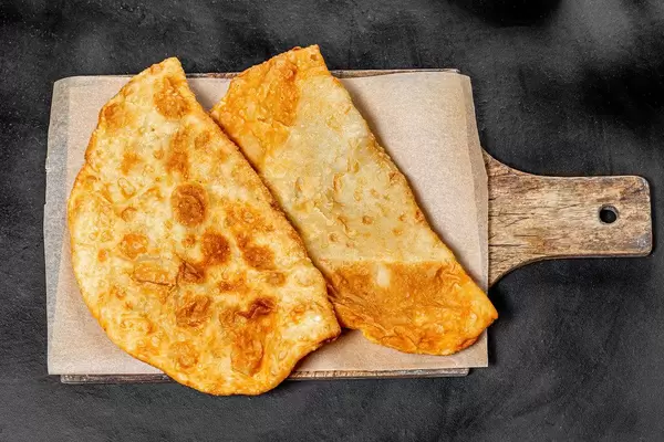 Big golden chebureks on kitchen board. Top view (Flip 2019)