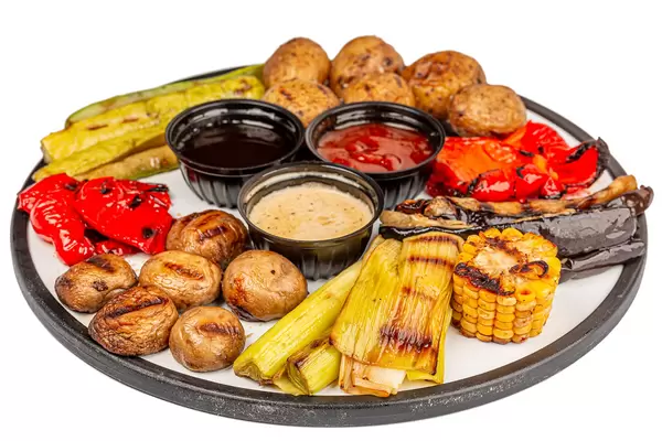 Big pieces of different grilled vegetables and champignons with sauces