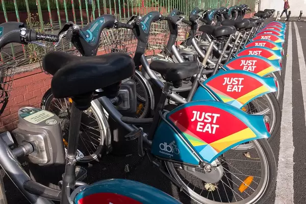 Bike sharing: rental bikes in a row at a station with just eat advertising cover