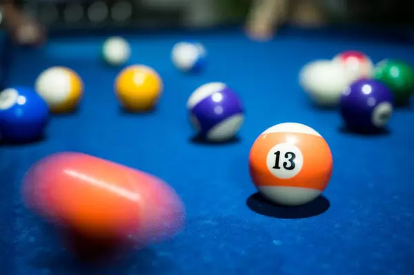 Billardkugel Nummer 13 umgeben von Bewegung, auf einem blauen Billardtisch