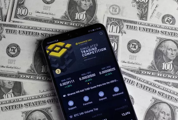 Binance App handelt mit Kryptowährung auf dem Mobiltelefon, mit 100 $ Noten