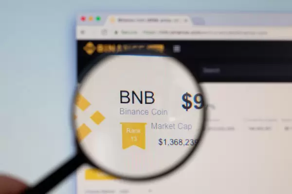 Binance Coin Logo am PC-Monitor, durch eine Lupe fotografiert