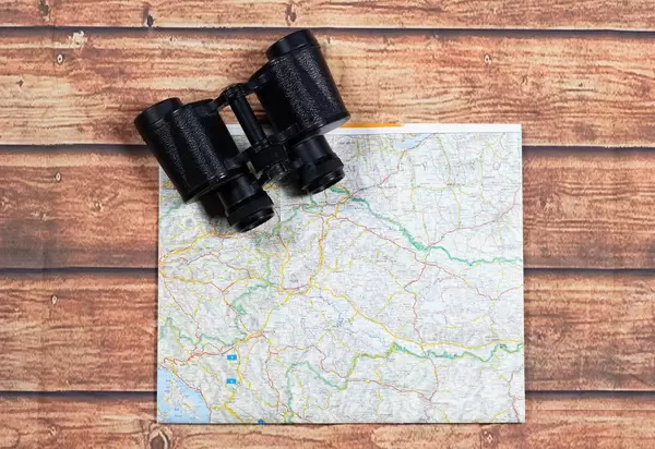 Binoculars and map on wooden table