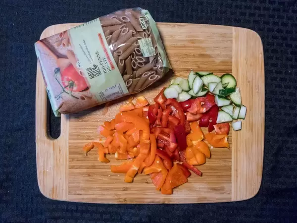 Bio Penne und geschnittene orangefarbene und rote Paprika und Gurke