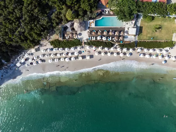 Bird's eye view of Limnonari beach with white hexagonal and straw parasols and swimming pool