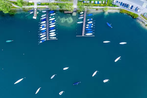 Bird's eye view: sailboats with covers resting in winter around two piers at Tegernsee lake in Bavaria