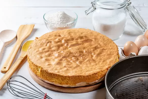 Biscuit, eggs, sugar, flour with baking dish and wooden kitchen utensils