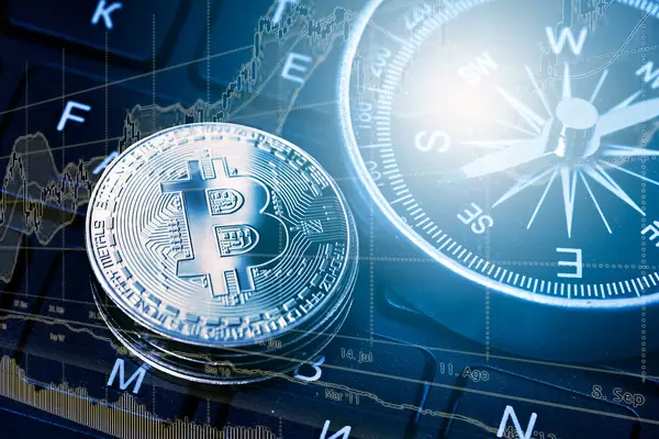 Bitcoin and compass on computer keyboard. Financial concept