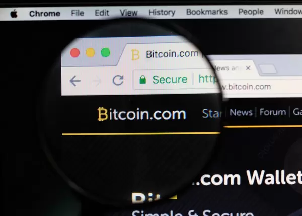 Bitcoin-Logo am PC-Monitor, durch eine Lupe fotografiert