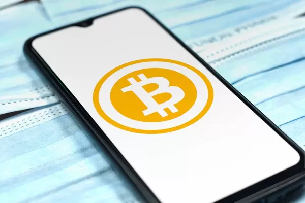 Bitcoin logo on smartphone screen over the face masks. Covid-19 effects on online business