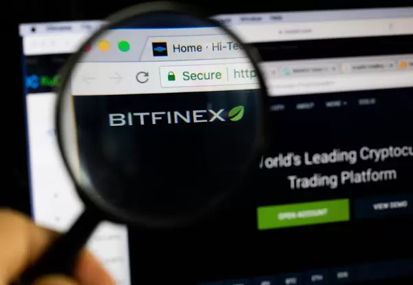 Bitfinex-Logo am PC-Monitor, durch eine Lupe fotografiert
