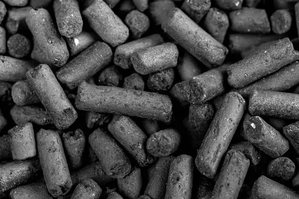 Black activated carbon granules background, close up