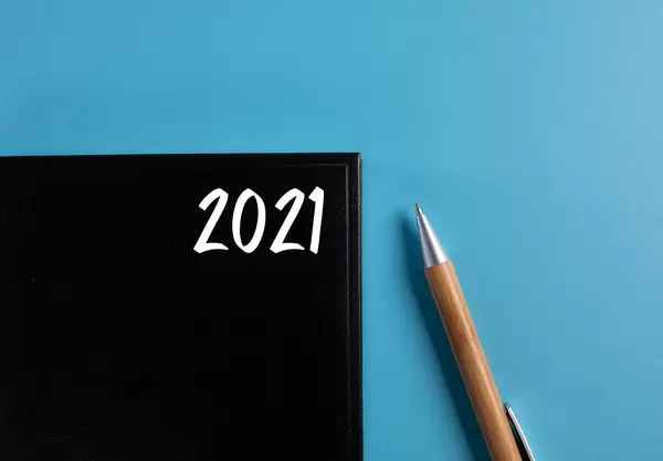 Black book with 2021 text and pen on blue background