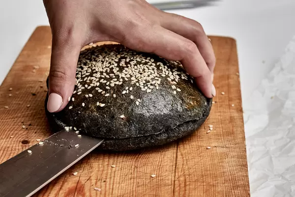 Black bread buns. Slicing black hamburger bread