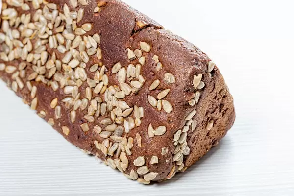 Black bread with sunflower seeds on white wooden background (Flip 2019)