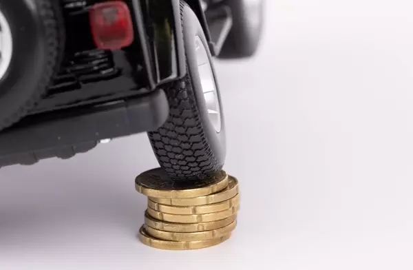 Black car on top of stack of coins on white background
