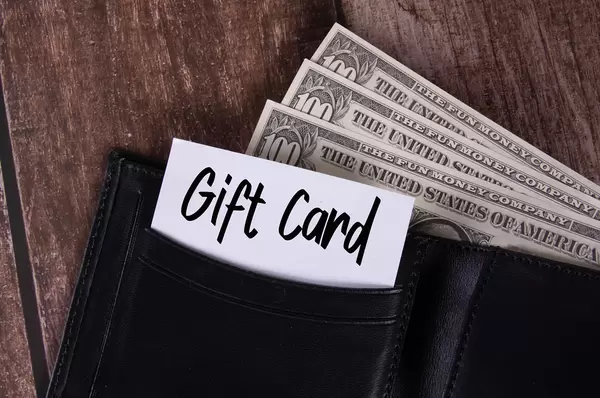 Black leather wallet with Dollar banknotes and note with Gift Card text