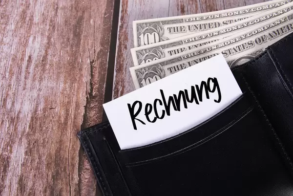 Black leather wallet with Dollar banknotes and note with Rechnung text