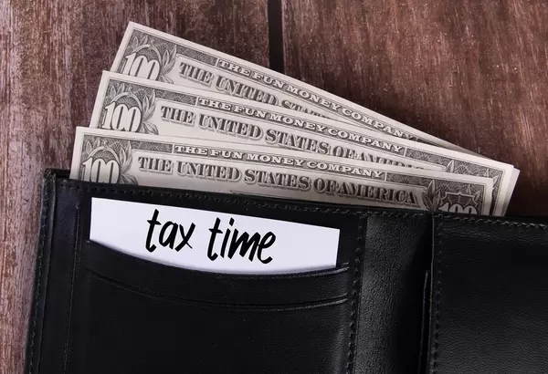 Black leather wallet with Dollar banknotes and note with Tax Time text