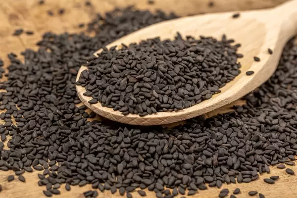 Black natural sesame seeds with wooden spoon