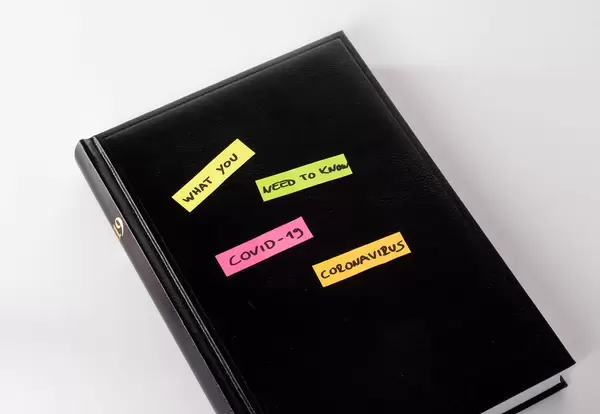 Black notebook with colorful stickers with What you need to know about Coronavirus text