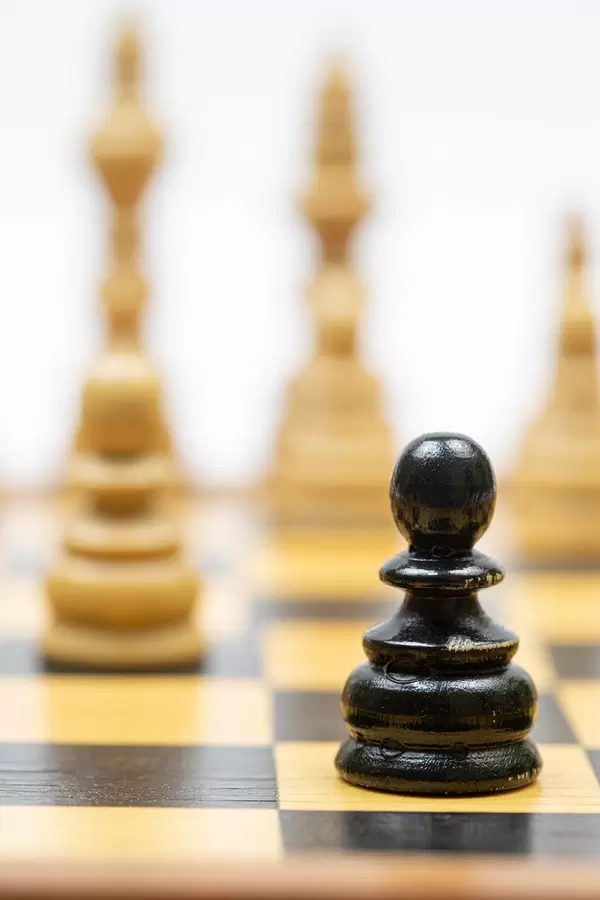 Black Pawn in the focus with Chess figures on the chess board