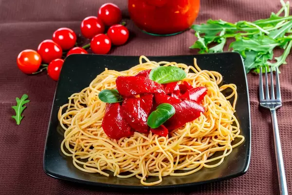 Black plate with delicious spaghetti with vegetables and fork (Flip 2019)