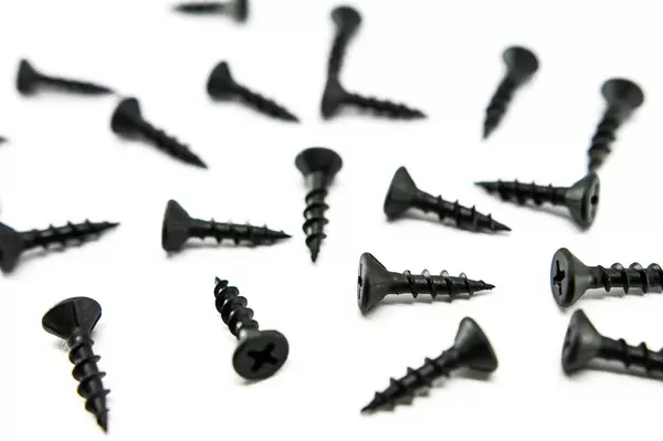 Black screws spread out on a white surface