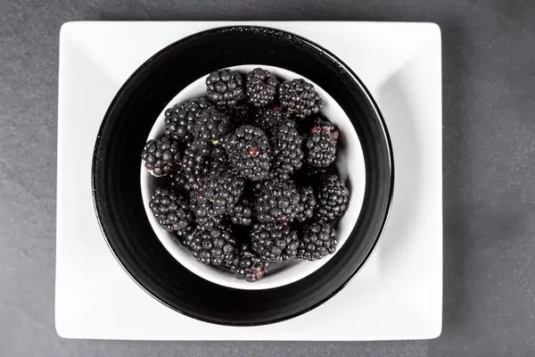Blackberries in bowls on a dark background, top view