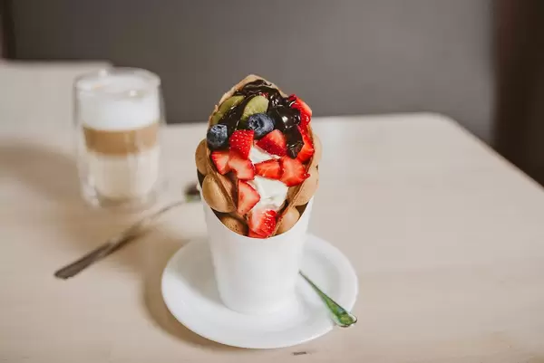 Blase-Waffeleis mit Beeren und Früchten, in einem weißen Papphalter