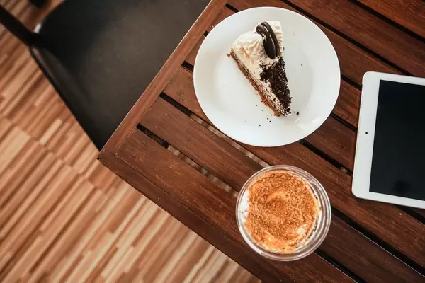 Blaubeer-Cheesecake mit Mango Eiscreme-Soda und einem iPad auf einem Holztisch - Aufsicht
