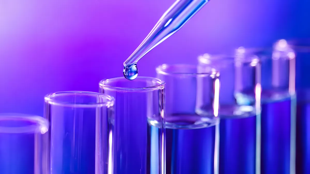 Blaue Flüssigkeit tropft aus Pipette in Reagenzglas