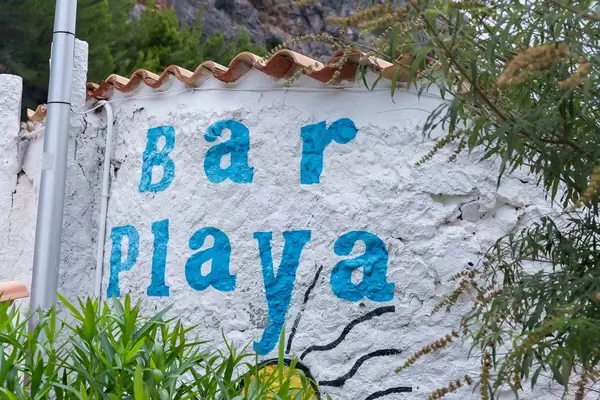 Blaue Schrift "Bar Playa" ("Strandbar") auf der weißen Wand in Port de Sa Calobra, Mallorca