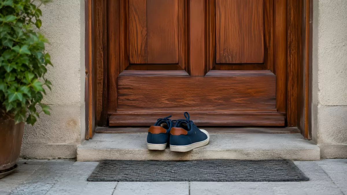 Blaue Sneaker vor einer Holztür am Hauseingang