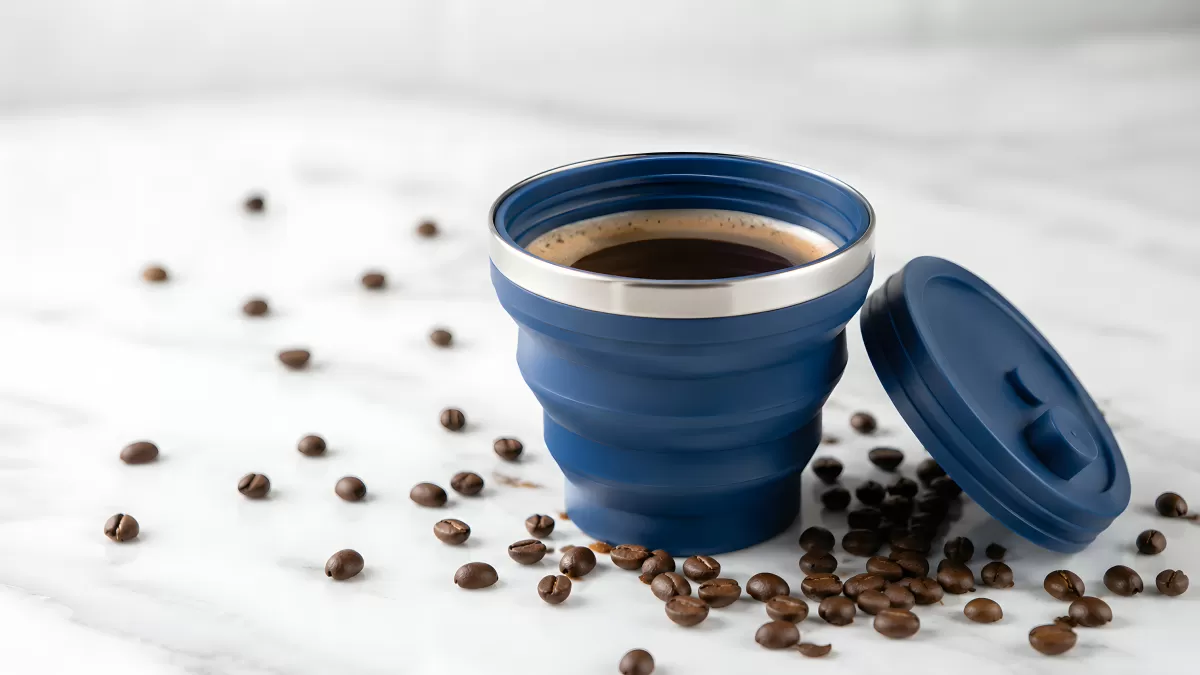 Blauer Faltbecher mit Kaffee und Kaffeebohnen