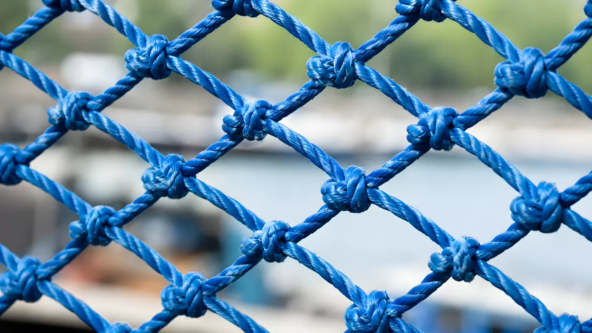 Blaues Fischernetz mit Knoten vor Hafenkulisse