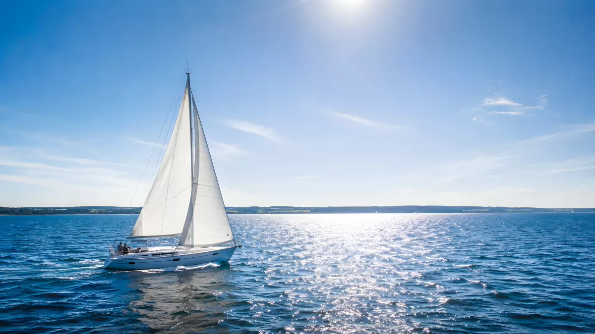 Blaues Meer mit weißem Segelboot im Sonnenlicht