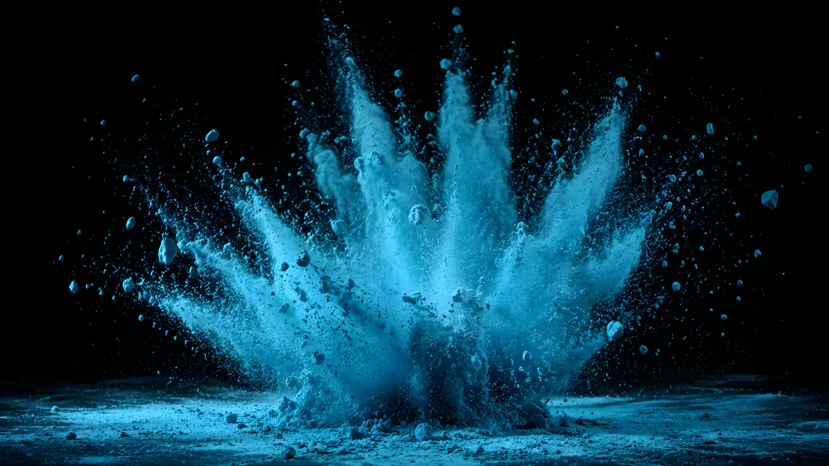 Blaues Pulver explodiert vor schwarzem Hintergrund
