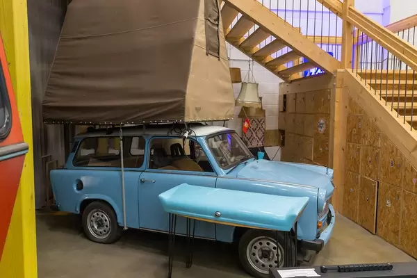 Blaues Retroauto mt weißem Dach und brauner Zeltkonstruktion auf dem Dach, als Wohnmobilalternative und Reisecaravan