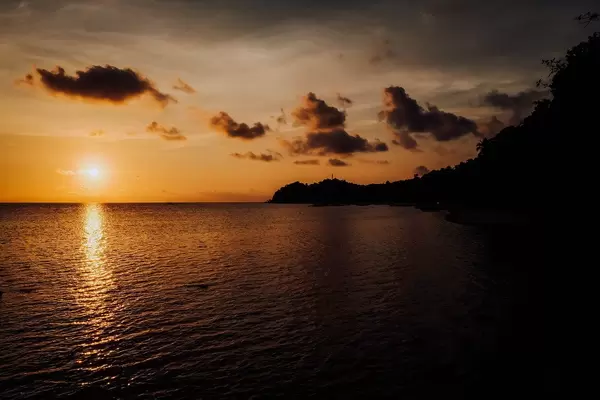 Blick auf den Sonnenuntergang in einem lokalen Badeort in Sipalay auf Negros, Philippinen, mit orangem Himmel und Reflexion auf dem Meer
