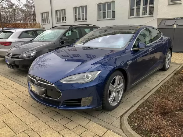 Blick auf Front und Seite eines Autos der Marke Tesla Model S 85D vor Haus geparkt