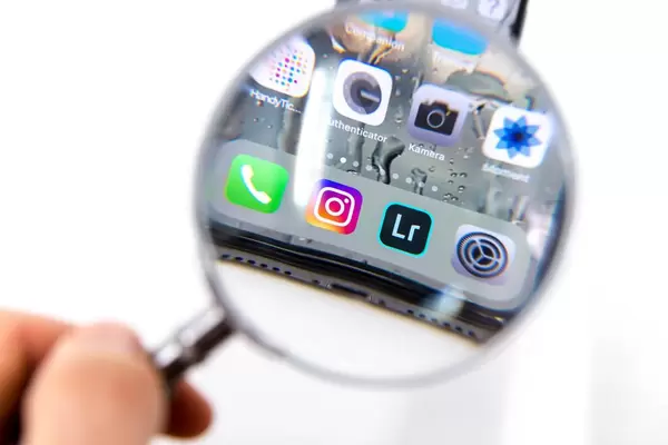 Blick durch Leselupe auf installierte Apps wie Instagram, Lightroom, Einstellungen, Kamera auf schwarzem Smartphone