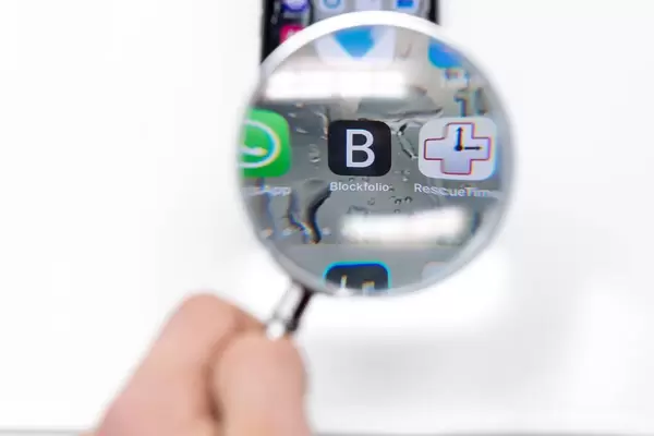Blick durch Lupe auf Blockfolio App Logo auf Mobiltelefon vor weißem Hintergrund
