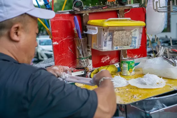 Blick über Schulter eines Mannes bei Zubereitung des typisch vietnamesischen Desserts Bo Bia in Vietnam