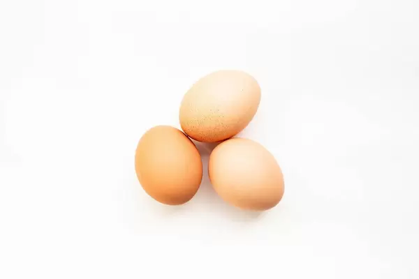 Blick von oben auf drei braune Eier vor weißem Hintergrund